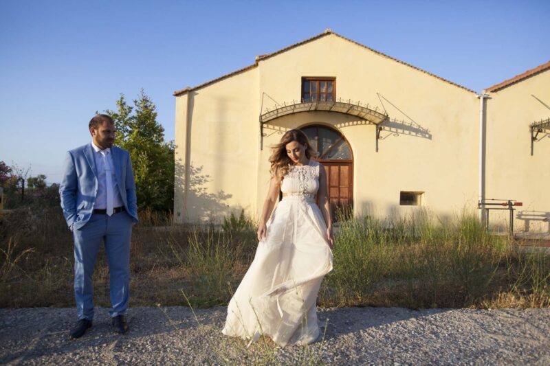 Ο γαμπρός κοιτάζει τη νύφη, στέκεται σε μια απόσταση και φτιάχνει το νυφικό της.Φωτογραφία Ιωαννα Χατζηδιάκου