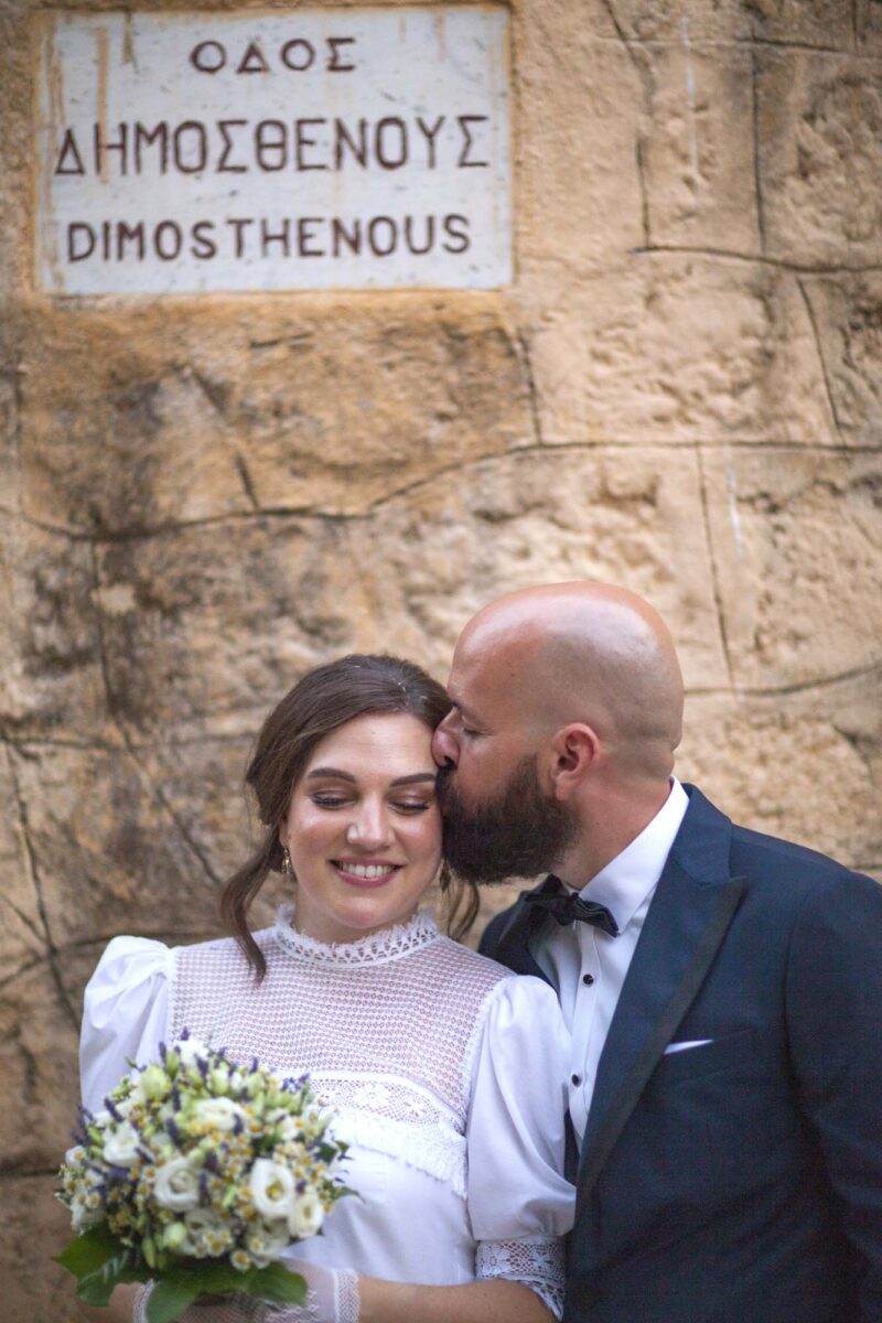 Wedding photography in Rhodes.Groom is giving a warm kiss to the bride